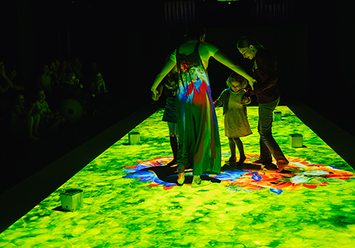 Tänzerinnen und Kinder auf Bühne mit Bildprojektionen