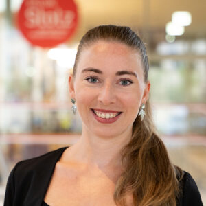 Portrait Maria Lackner, Betriebsleiterin Salon Stolz, lächelnd in Kamera blickend
