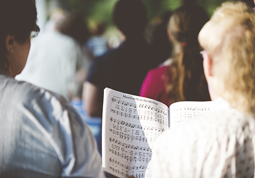 Rückenansicht von Menschen die zu Noten singen